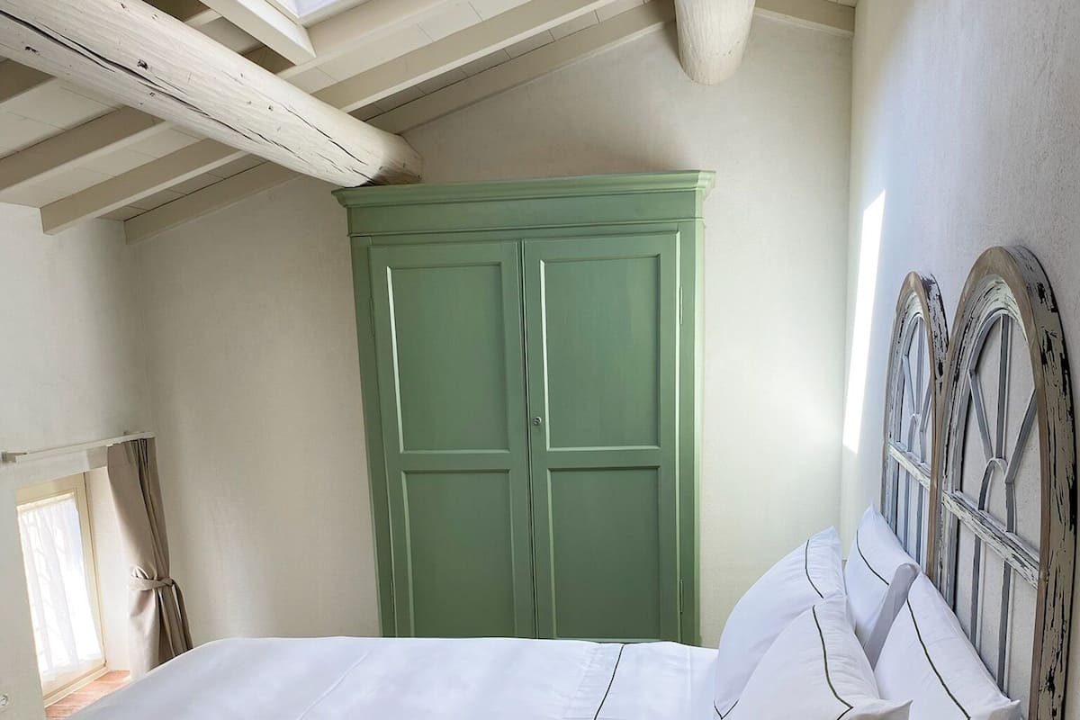 A bedroom with a bed, a green wardrobe, and a skylight.