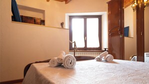 A hotel room with a bed, towels, a window, and a wooden wardrobe.