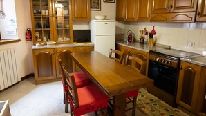 A kitchen with wooden cabinets, a refrigerator, a stove, and a dining table with chairs.