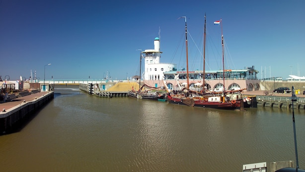A harbor with boats docked, a lighthouse, and a bridge in the background. - Logement Garjen (Harlingen)