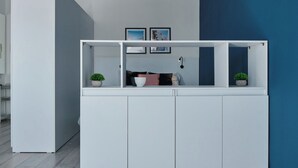 Een moderne badkamer met witte kasten, een spiegel en twee ingelijste foto’s aan de muur.