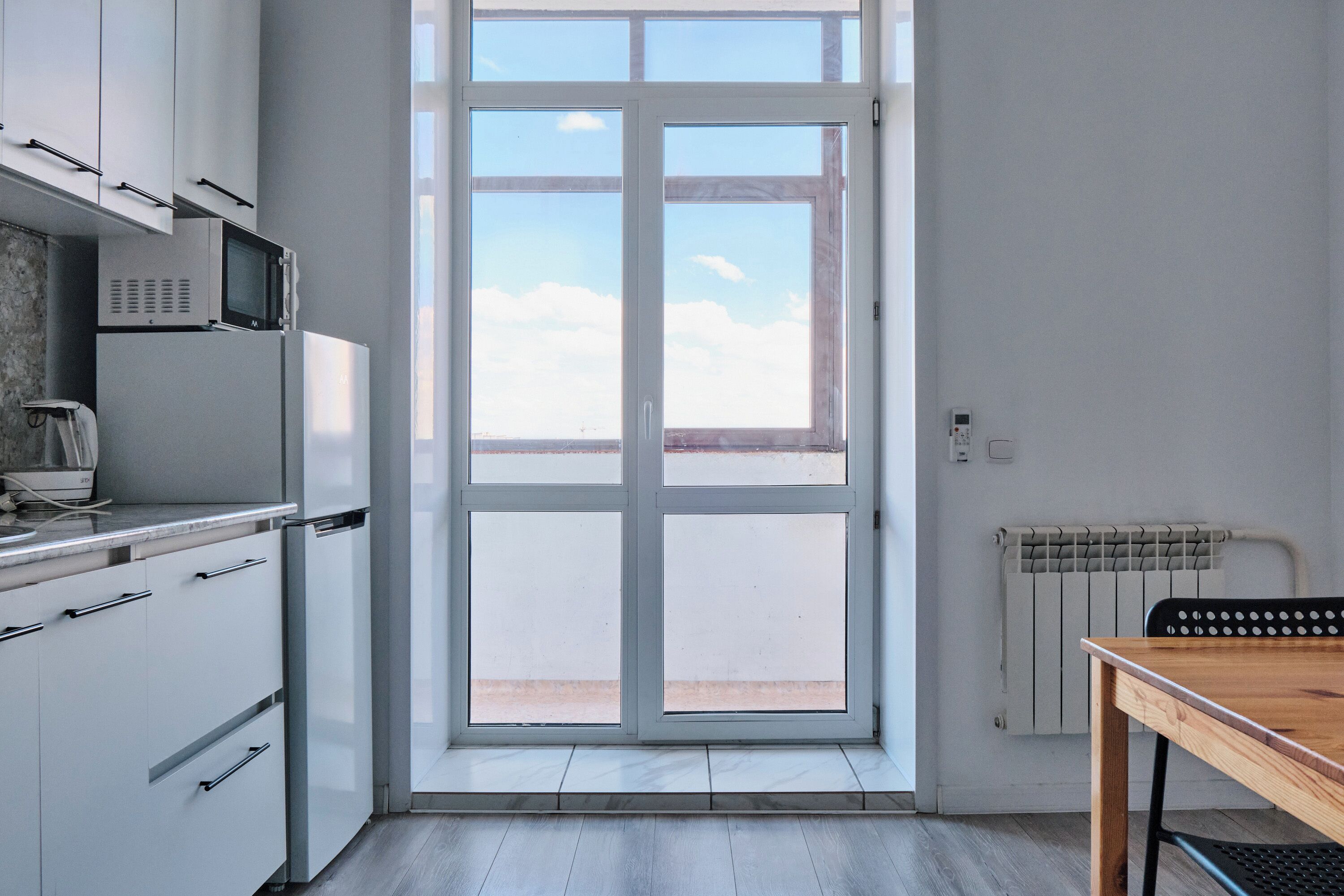 A modern kitchen with white cabinets, a built-in microwave, and a large sliding glass door leading to an outdoor patio.