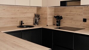 Een moderne keuken met zwart-wit keukenkastjes, een houten aanrechtblad en roestvrijstalen apparatuur.