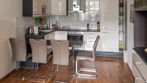 A modern kitchen with white cabinets, a stainless steel stove, and a dining area with four chairs.