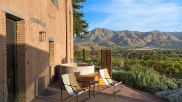 A patio with two lounge chairs and a small table, overlooking a mountainous landscape.