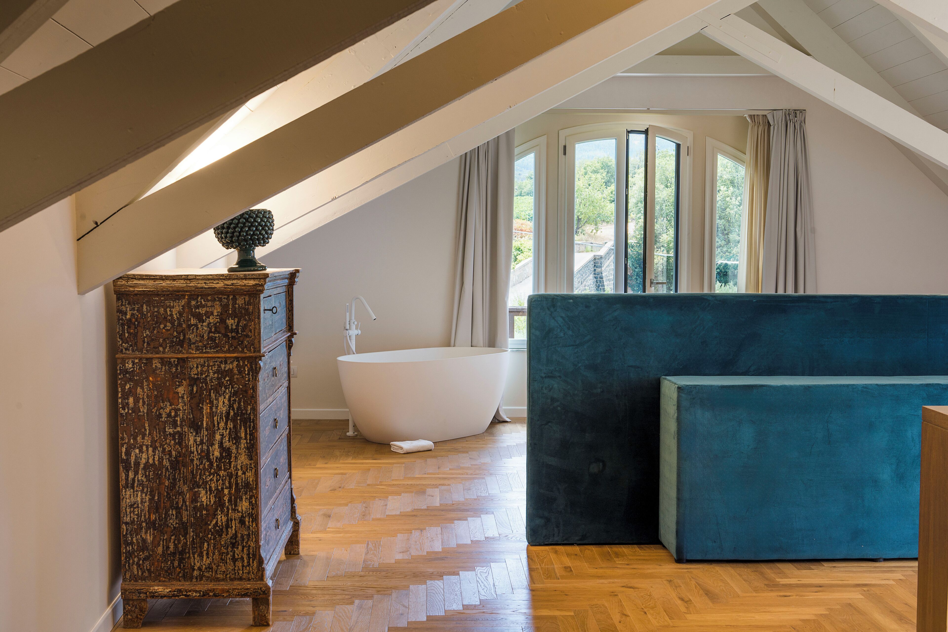 Una habitación con tocador de madera, una bañera y un sofá azul.
