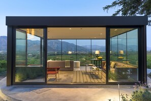 A modern interior with a sofa, chairs, and a table, featuring large glass walls and a view of the outdoors. - Dimora Cottanera (Castiglione di Sicilia)
