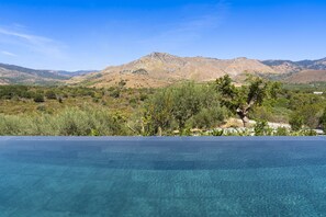 Una piscina al aire libre, sombrillas, sillones reclinables de piscina