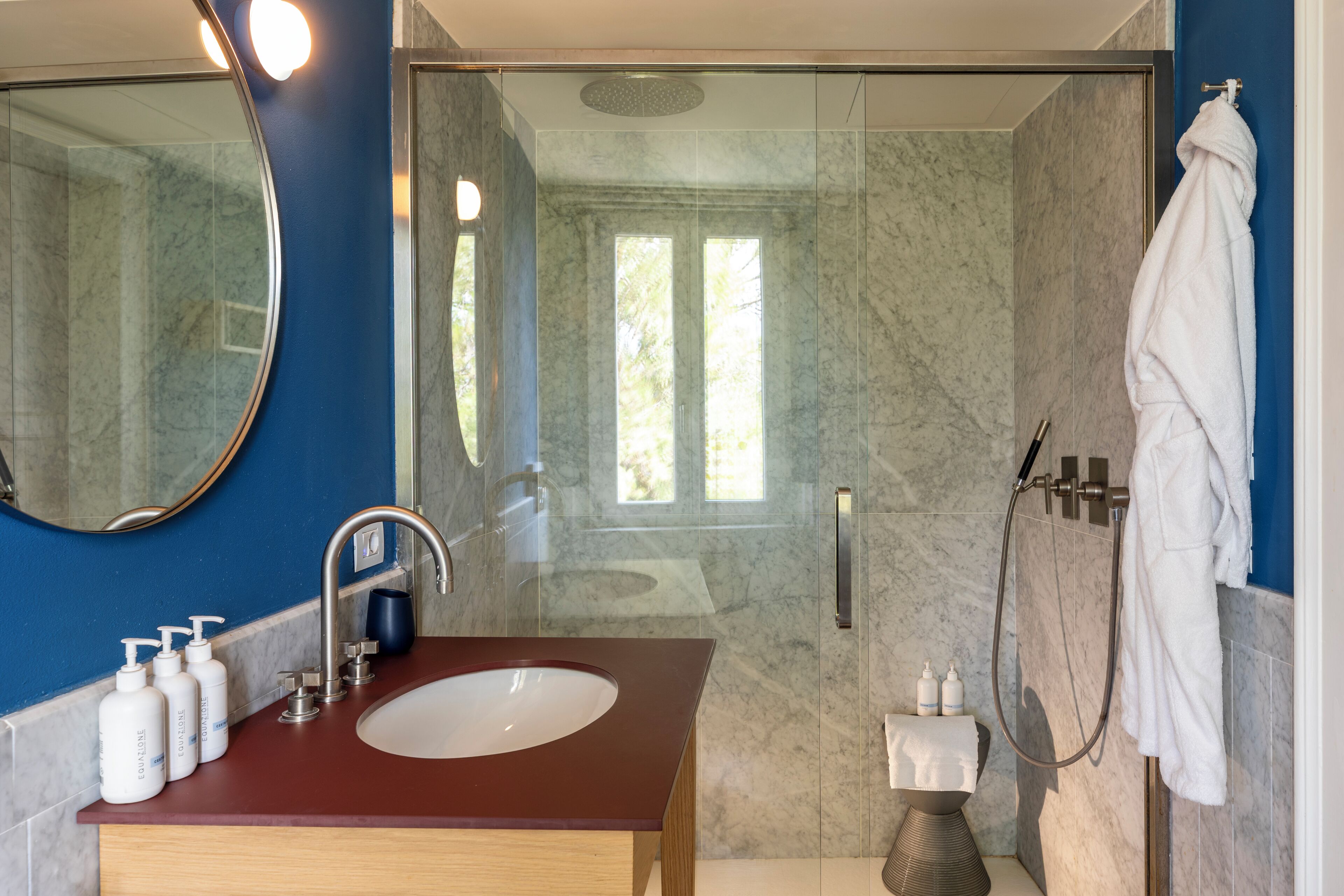 Un bagno con lavabo in marmo, uno specchio, una doccia e un portascopevoli.