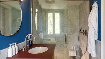 Un bagno con lavabo in marmo, uno specchio, una doccia e un portascopevoli.