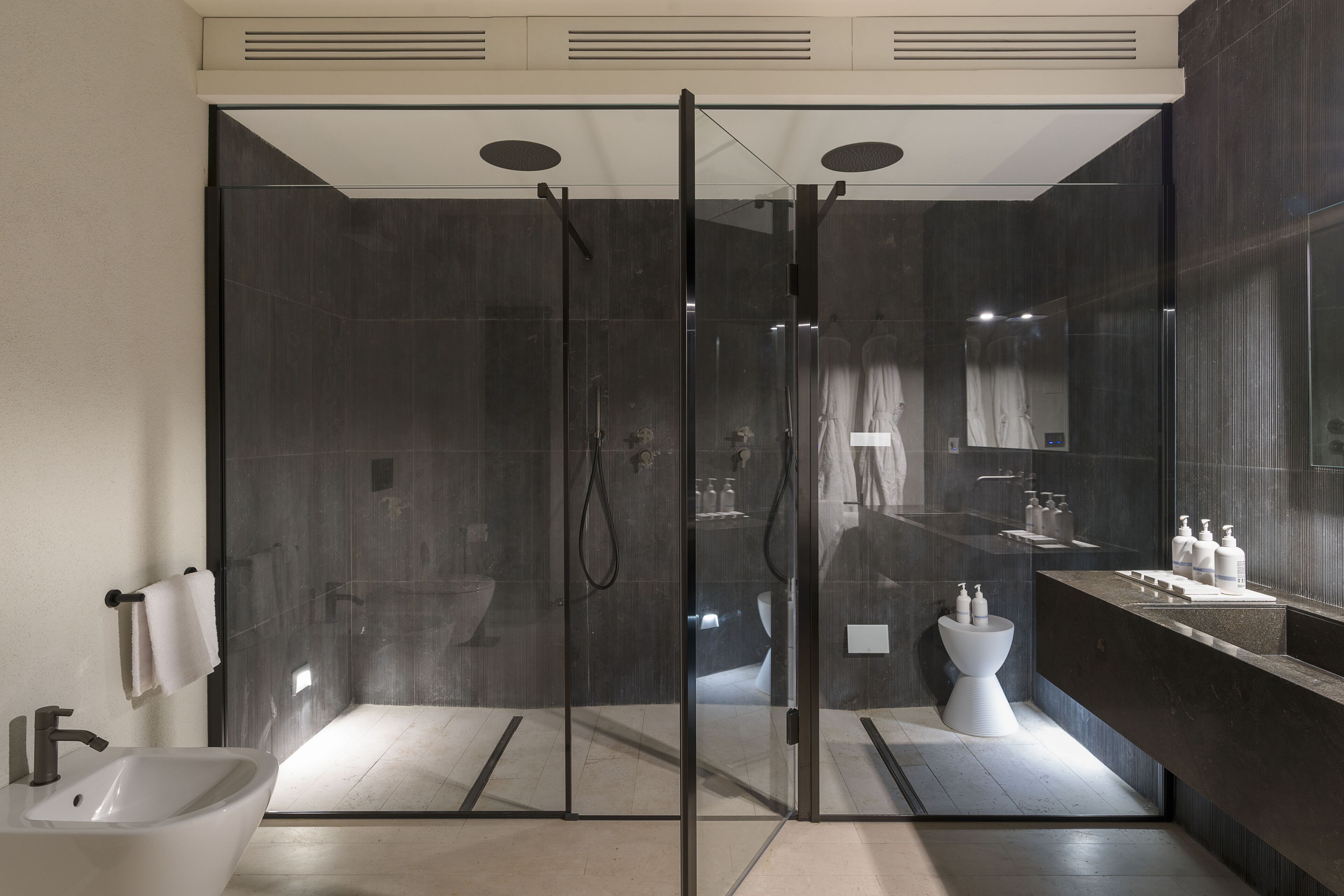A modern bathroom with a glass-enclosed shower, a white sink, and a vanity with toiletries.