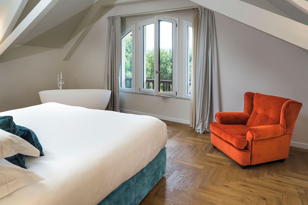 Een slaapkamer met een bed, een stoel en een raam met gordijnen.