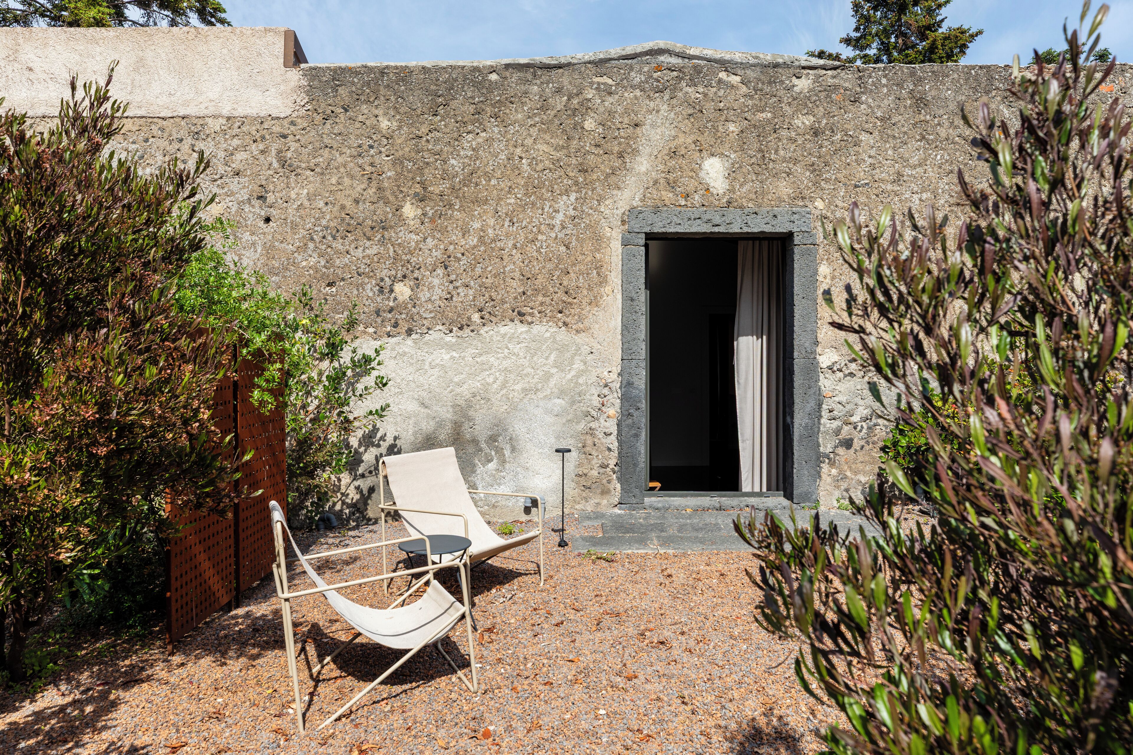 A rustic stone building with a doorway, a hammock, and a small table.