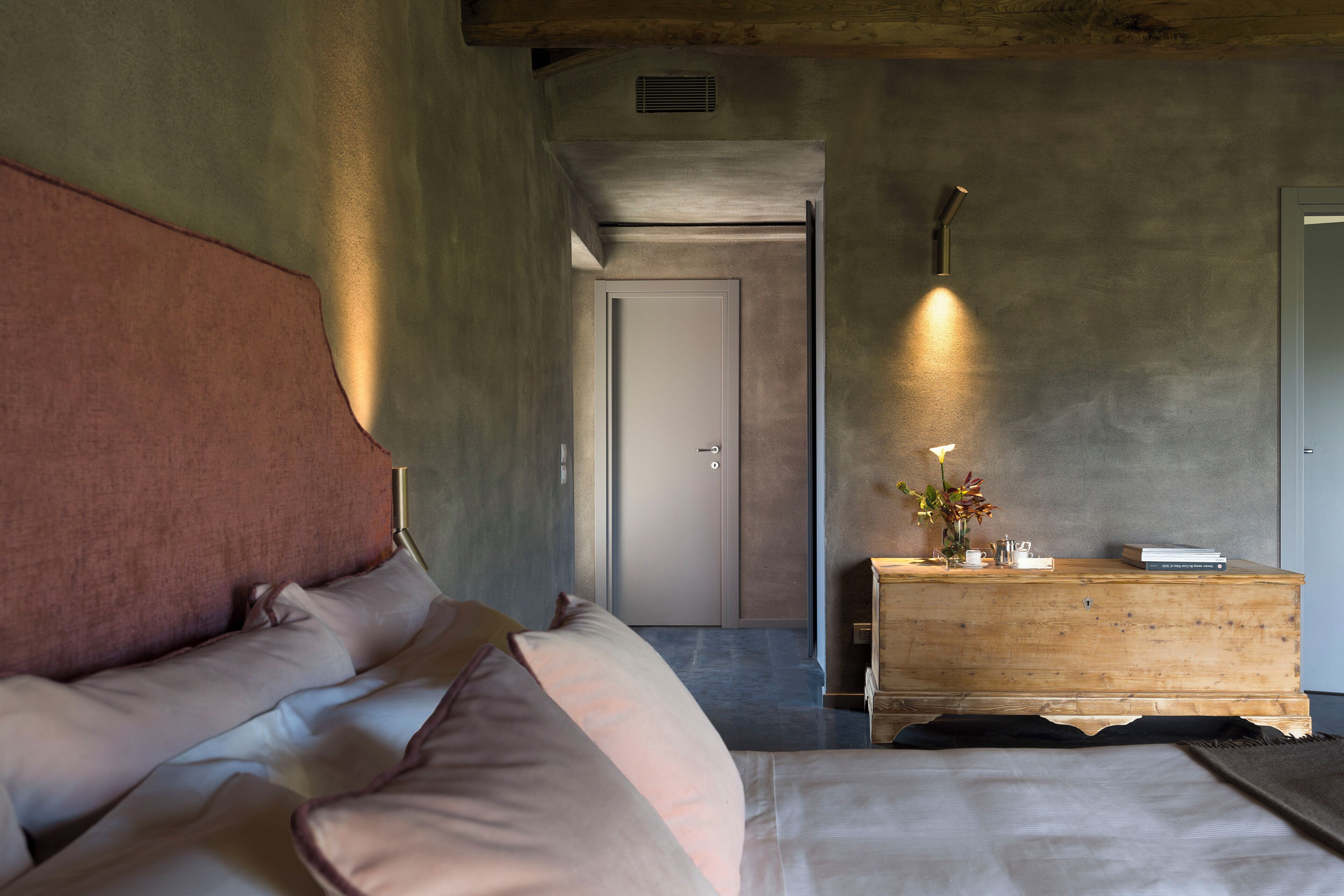 A bedroom with a bed, a wooden dresser, and a door in the background.