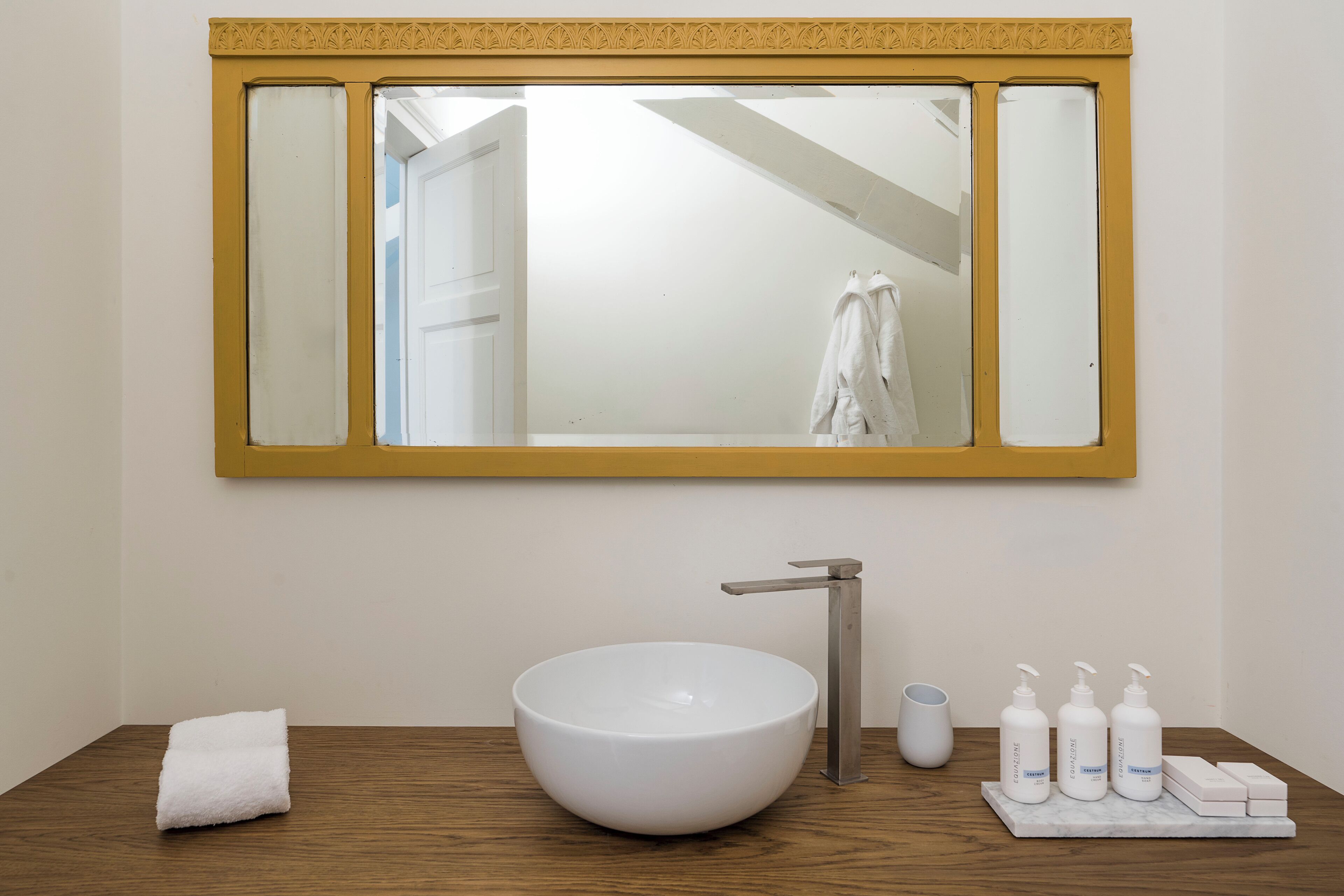 Une salle de bain avec un lavabo blanc, une serviette et des articles de toilette posés sur le comptoir.