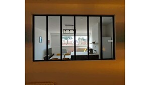 Una habitación con un espejo grande que refleja una sala de estar con un sofá, una mesa de centro y una ventana.