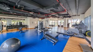 A gym with exercise equipment, a blue floor, and large windows. - Maison Privee - Classy Apt w/ Terrace & Direct Burj Khalifa Views (Dubai)
