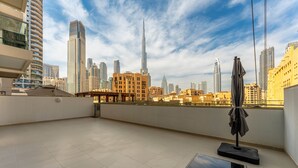 A rooftop terrace with a clear view of the city skyline, including tall buildings and a distinctive skyscraper. - Maison Privee - Classy Apt w/ Terrace & Direct Burj Khalifa Views (Dubai)