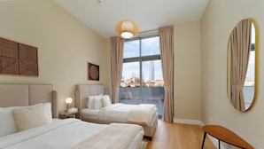A hotel room with two beds, a large window with curtains, a round mirror, and a wooden bench. - Maison Privee - Classy Apt w/ Terrace & Direct Burj Khalifa Views (Dubai)