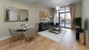 A modern living room with a dining area, a sofa, and a large window with curtains. - Maison Privee - Classy Apt w/ Terrace & Direct Burj Khalifa Views (Dubai)
