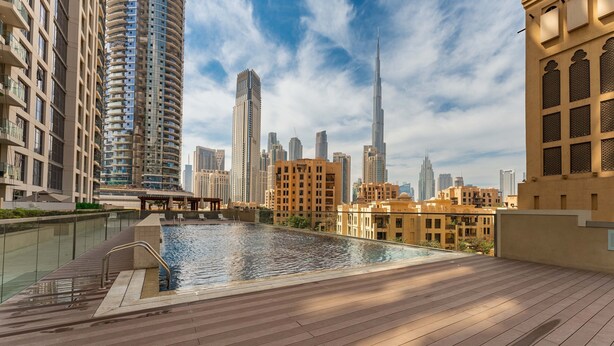 A rooftop pool with a city skyline in the background, including a prominent skyscraper. - Maison Privee - Classy Apt w/ Terrace & Direct Burj Khalifa Views (Dubai)