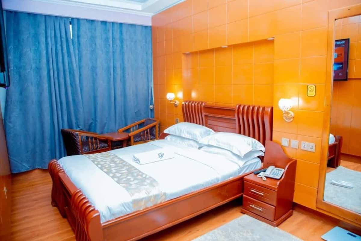Una habitación de hotel con una cama de madera, un escritorio y un espejo.