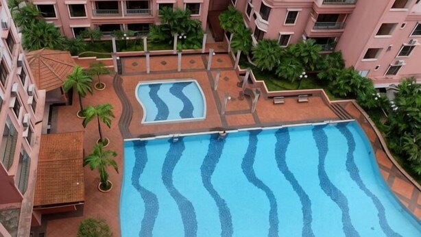 A rooftop swimming pool with wavy patterns, surrounded by greenery and a multi-story building. - Nana Marina Court (Kota Kinabalu)