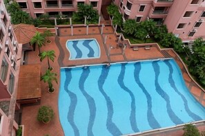 Ein Dachpool mit wellenartigen Mustern, umgeben von Grünpflanzen und einem mehrstöckigen Gebäude.