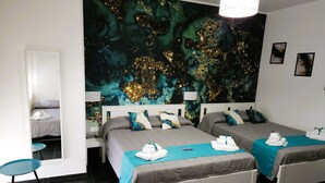 Une chambre d’hôtel avec deux lits, une grande fresque murale abstraite et une petite table ronde.