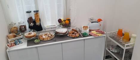 A breakfast buffet with various pastries, fruits, and beverages.
