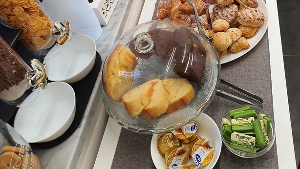 Une table de buffet proposant divers plats, notamment des pâtisseries, des sandwichs et une tarte.