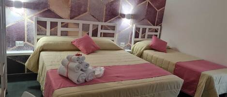 A hotel room with two beds, each with a headboard, and a window. There are towels on the beds and a chair in the corner.