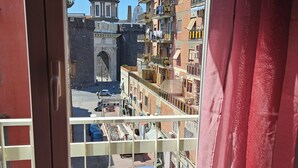Une vue depuis un balcon donnant sur une rue, avec un bâtiment historique doté d’un dôme et d’une arche.