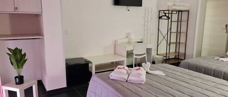 Une chambre d’hôtel avec deux lits, un bureau, une chaise, une télévision, une armoire et une plante.