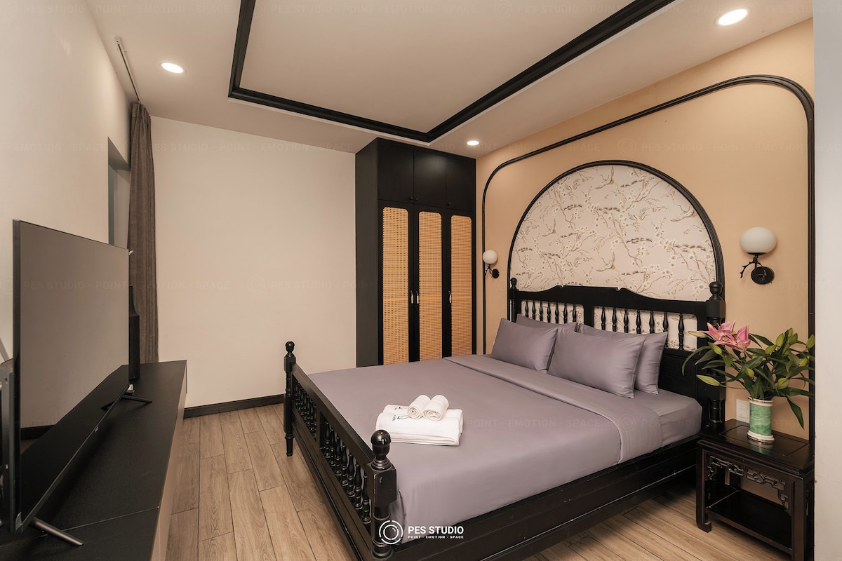 Un dormitorio moderno con cama, televisor, mesita de noche y lámpara de pared.