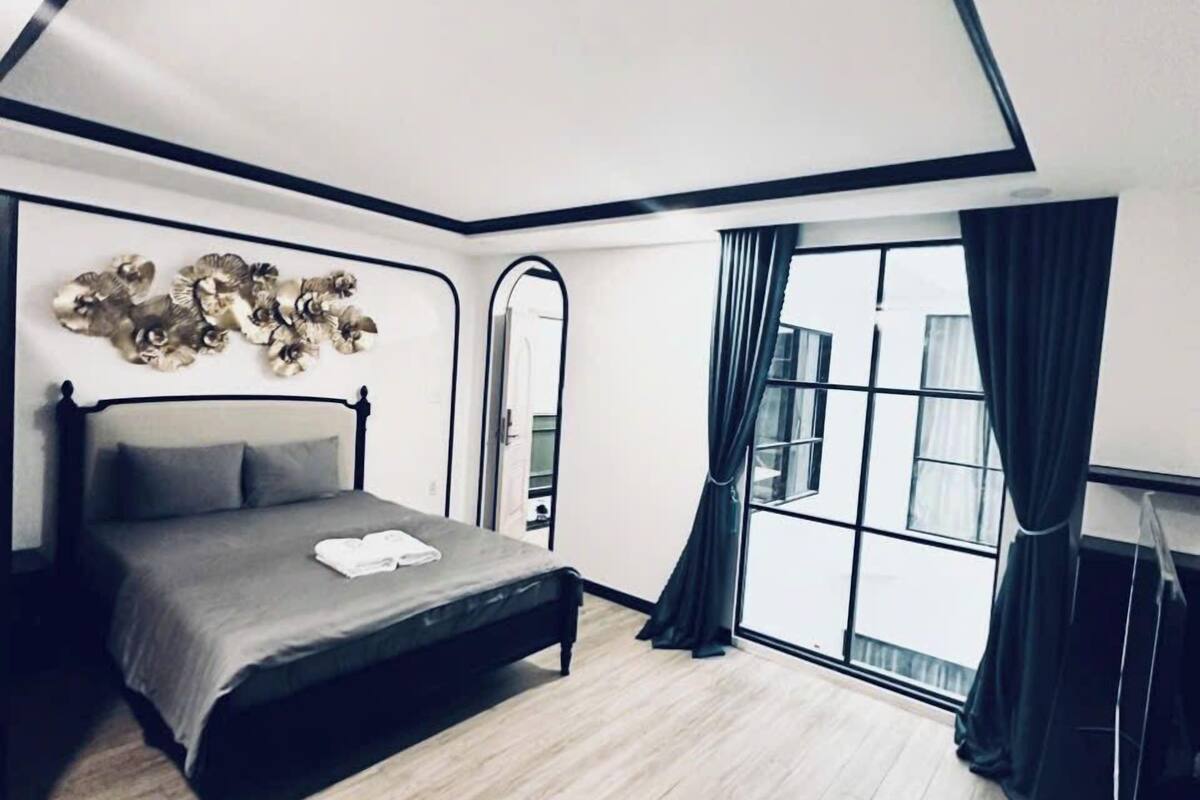 Um quarto moderno com cama, uma janela grande e um design de teto singular.