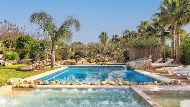 A swimming pool with a hot tub, surrounded by palm trees and rocks. - Petit Bijouc by Rentallorca (Can Picafort)