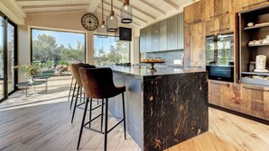 A modern kitchen with a large island, wooden cabinets, and a view of the outdoors. - Petit Bijouc by Rentallorca (Can Picafort)