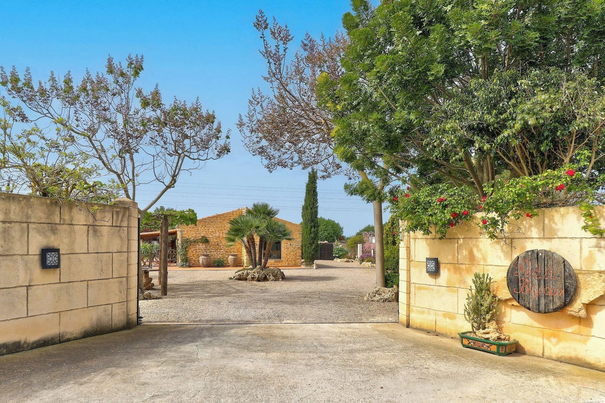 A gated entrance with a gravel path leading to a building with a brick facade.