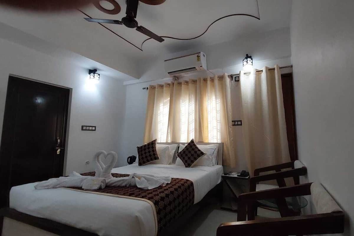 A hotel room with a bed, a desk, a chair, a ceiling fan, and a window with curtains.