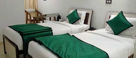 A hotel room with three beds, a chair, an air conditioning unit, and a small table.
