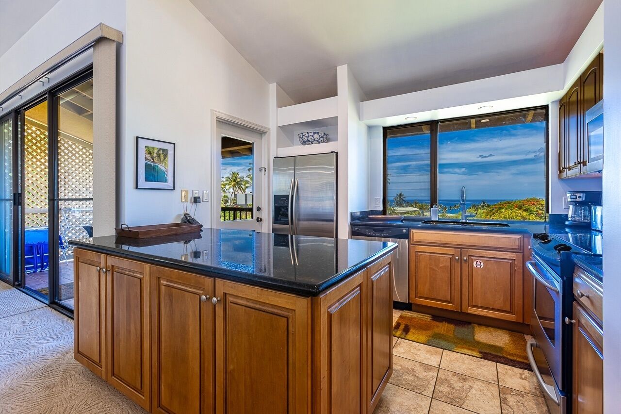 A modern kitchen with a large island, stainless steel appliances, and a view of the ocean.