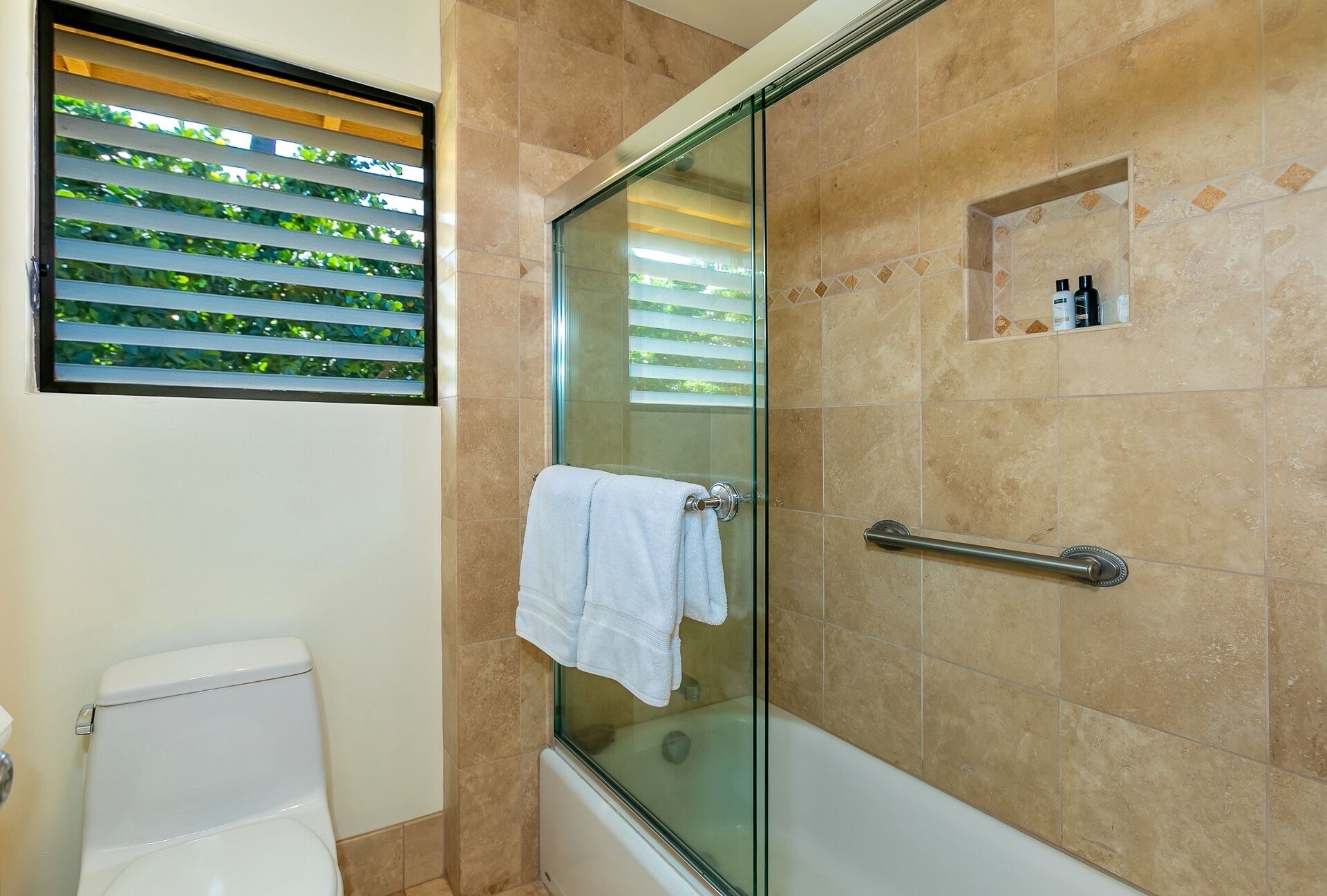 A modern bathroom with a glass shower enclosure, a white toilet, and a bathtub.
