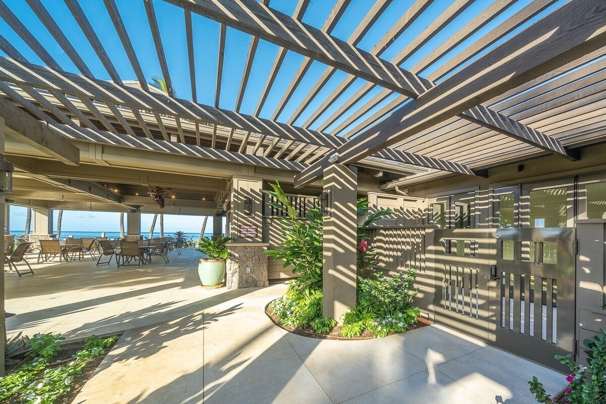 An outdoor patio area with a pergola, seating, and a view of the ocean.