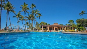 A swimming pool surrounded by palm trees, with a building in the background. - Wailea Ekahi Two Bedrooms - Ocean View by Coldwell Banker Island Vacations (Kihei)