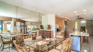 A modern kitchen with a glass dining table, wicker chairs, and a refrigerator. - Wailea Ekahi Two Bedrooms - Ocean View by Coldwell Banker Island Vacations (Kihei)