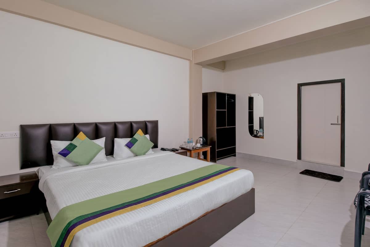 Una habitación de hotel con cama, mesita de noche, armario y puerta.