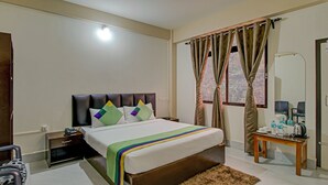 A hotel room with a bed, bedside table, nightstand, and a mirror. - Treebo Staying Center (Shillong)