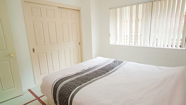 Un dormitorio con cama, una puerta blanca y una ventana con persianas.