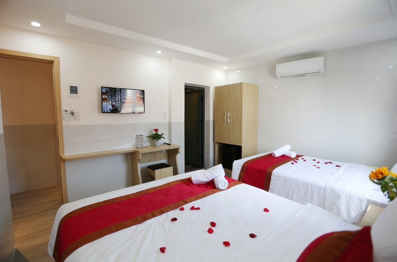 Quarto de hotel com duas camas, uma mesa de escritório, uma TV e um ar condicionado.
